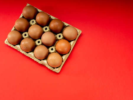 Eggs in a yellow cardboard egg cup on a red background