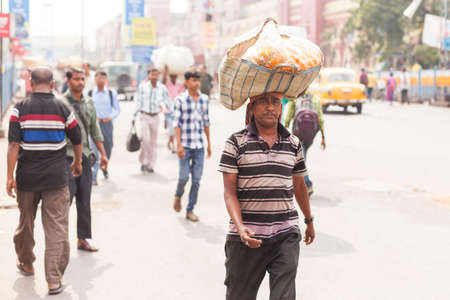 KOLKATA, INDIA - 22 Oct 2016: A man carries a basket of flowers balanced on his head near Howrah Station on October 22, 2016 in Kolkata (Calcutta), Indiaのeditorial素材