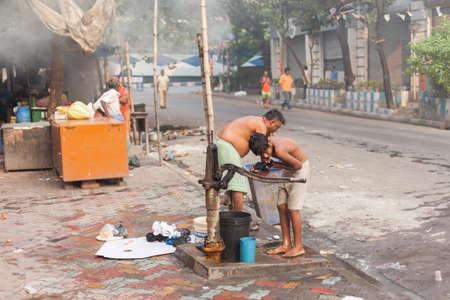 KOLKATA, INDIA - 22 Oct 2016: Men wash themselves from a pump near Sudder Street on the morning of October 22, 2016 in Kolkata (Calcutta), Indiaのeditorial素材