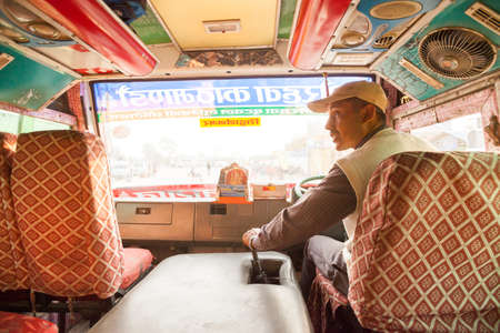 Sunauli, Nepal - 29 Oct 2016: Bus driver in a colorfully painted local bus on October 29, 2016 in Sunauli, Nepalのeditorial素材