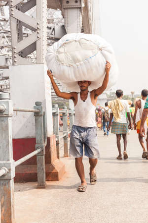 KOLKATA, INDIA - 22 Oct 2016: A man carries a load on his head across the Howrah Bridge on October 22, 2016 in Kolkata (Calcutta), Indiaのeditorial素材