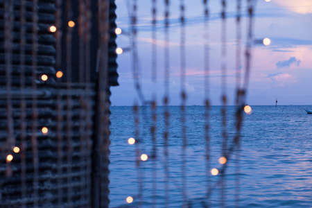 Strings of seashells and christmas lights on a tropical island at duskの写真素材