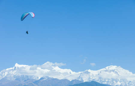 Tandem paragliders float over Nepal with the Annapurna Himalayas in the backgroundの写真素材