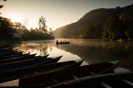 Ferryman takes passengers across Fewa lake at sunriseの写真素材