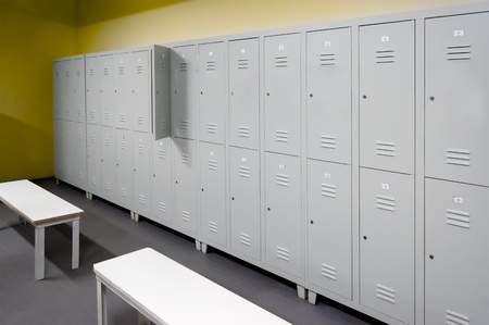 Row of steel lockers along the yellow wall and two white benchesの写真素材