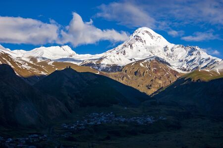 View of Kazbegi mountain and Stepantsminda village at sunriseの写真素材