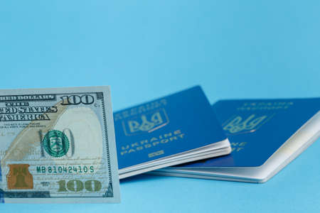 100 dollars in the front smooth, in the background 2 Ukrainian foreign passports out of focus on a...