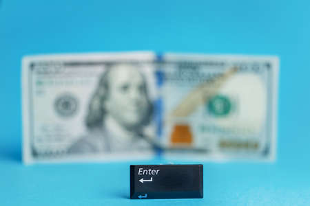 enter button in the foreground blurred banknote one hundred dollars centered on a turquoise backgroundの写真素材