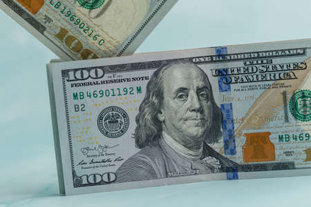 One hundred dollars banknote stands on top drops 100の写真素材