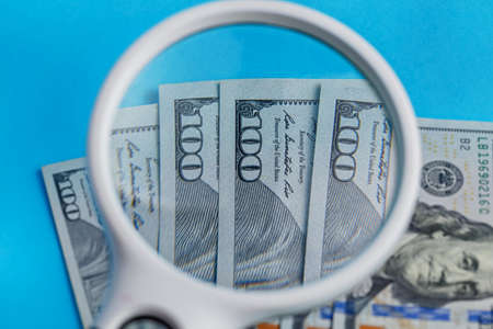 Deck of lying 100 dollars through a magnifier close-up on a blue backgroundの写真素材