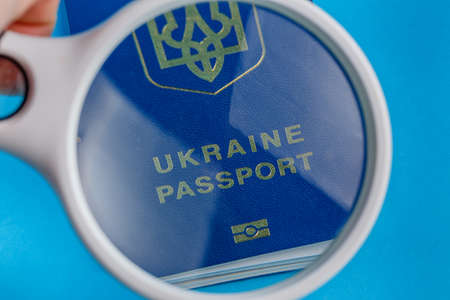 Magnifying glass shows biometric Ukrainian passport is inscribed Ukrainian passport on blue backgroundの写真素材