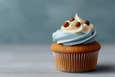 Tasty cupcake with light blue swirl cream and chocolate pieces on neutral background ideal for pastry shop marketing and recipe blogsの素材