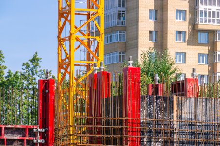A tower construction crane on the background of a blue sky with clouds. Boom rotary crane with boom. Construction of apartment buildings in the city. Construction of high rise buildings.の写真素材