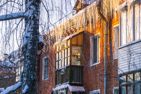 In winter, icicles hang from the roof of an old house. frozen water. Winter view of an old house in the city. An old house with a balcony.の写真素材