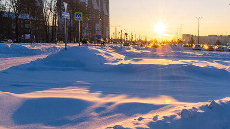 Snowdrifts in the city. Winter landscape in the city. Bright sun in winter and snow drifts. Parking and snow in winter in the city.の写真素材