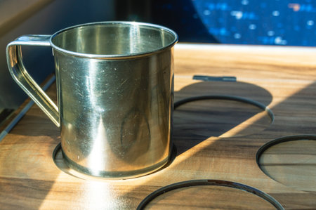Aluminum mug on the table in a special place for a stable position. A metal mug on the table on the train. Traveling by rail.の写真素材