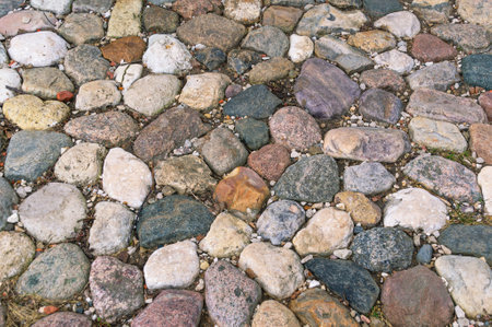 cobblestone pavement. Background of cobblestones of different colors on the road. Ancient rough...