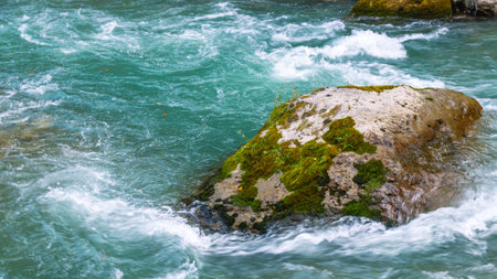 A huge gray boulder lies in a mountain river. A mountain river with clear and transparent water. Landscape with a view of gray stones in a mountain river.の写真素材