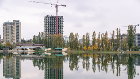 High-rise buildings are being built next to the pond. Reflection of buildings and trees under...