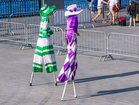 Clowns on stilts in colorful costumes. Summer holiday with clowns on the river embankment.の写真素材