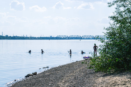 Active recreation on the river in summer. view of the river. Bathing people in the river. Children and parents swim in the river in warm weather. Children play near the shore in the river.の写真素材