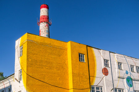 The production building is painted yellow and the sky is blue. Industrial building and factory brick pipe.の写真素材
