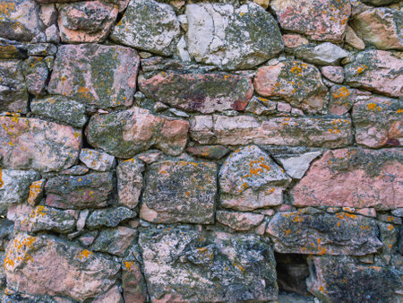 The wall of an ancient tower built of stones in the mountains to protect against attack. ancient masonry. An ancient structure high in the mountains.の写真素材