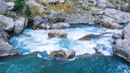 A huge gray boulder lies in a mountain river. A mountain river with clear and transparent water....