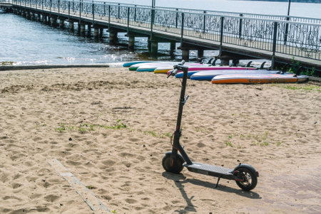 The scooter is on a sandy beach. There are sap boards behind the scooter, and a berth for yachts and ships is also visible. Sandy beach on the shore. vacation at the sea.の写真素材