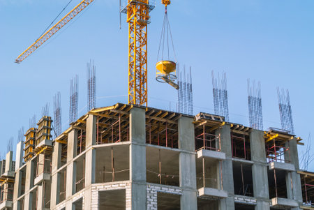 Buckets for concrete on the slings of a tower crane. Equipment for the construction and lifting of bulky loads during the construction of buildings. A tower crane lifts a bucket of cement mortar.の写真素材