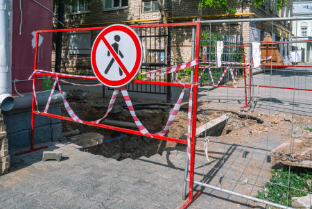 The road sign "Pedestrian traffic is prohibited". The fence is installed on the street next to the trench. Road works on the street in the city. Excavation work on the sidewalk.の写真素材