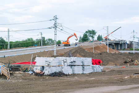 View of the road bridge construction site. Road equipment and construction materials during the construction of the bridge. The excavator works during the construction of the road. Earthworks.の写真素材
