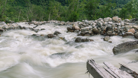 The bubbling glacial-clear water of a mountain river with large stones high in the mountains. Environmentally friendly water flows down from a glacier in the mountains. Nature in the mountains.の写真素材