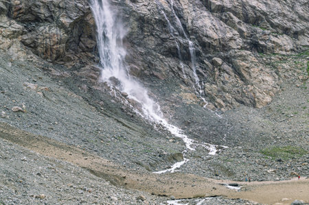A large waterfall was formed as a result of melting ice on the top of the mountain. Water flows down from a glacier in the mountains. Nature in the mountains. Landscape with a view of the glacier.の写真素材
