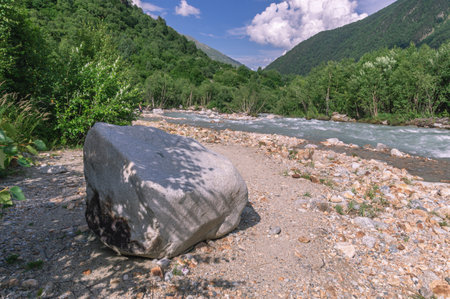 The bubbling clear water of a mountain river with large stones high in the mountains. Clean water flows down from a glacier in the mountains. Landscape in the mountains. Uncontaminated environment.の写真素材