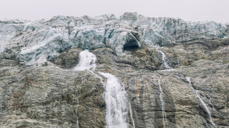 A large waterfall was formed as a result of melting ice on the top of the mountain. Water flows down from a glacier in the mountains. Nature in the mountains. Landscape with a view of the glacier.の写真素材