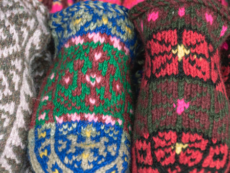Multicolored wool knitted handmade mittens for the cold season. Things made of natural yarn. Winter clothes made of natural wool. Knitting with needles. Knitted fashion.の写真素材