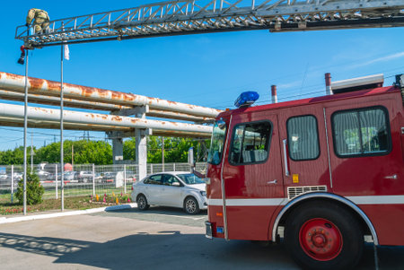 A fire truck for delivering firefighters to the fire site and supplying extinguishing agent for extinguishing. The firefighter is on the retractable ladder of the fire truck. Emergency rescue service.の写真素材