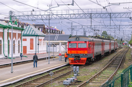 Electric transport on the railway. Contact power lines for commuter trains. People get on an electric train on the platform. Railway tracks at the railway station.の写真素材