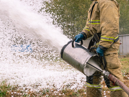 A firefighter in protective clothing extinguishes a fire with foam. A firefighter extinguishes a...