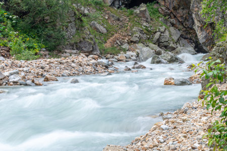 A river with clear water flows out of a mountain gorge. Environmentally friendly water flows down from a glacier in the mountains. Nature in the mountains. View of the mountain river in summer.の写真素材