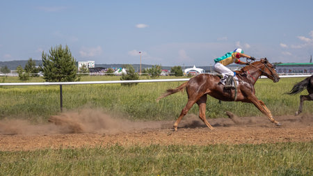 Horse racing at the racetrack. A horse led by a jockey. Horse riding competitions. A rider on a horse. Horses gallop along the racetrack track.の写真素材