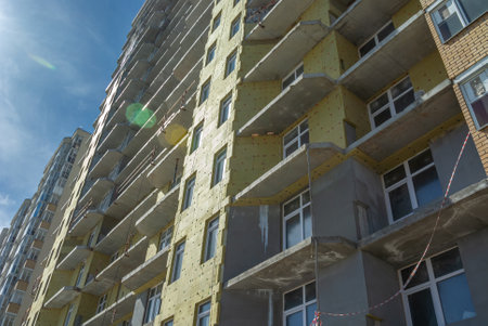 To keep warm in winter, soft insulation is installed on the exterior walls of the building. Laying of thermal insulation material on the walls. Insulation of the house. Plastering of the facade walls.の写真素材