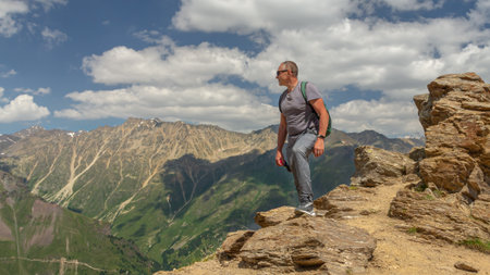 A man looks at the high snow-capped mountains. The conquest of the mountains. The rocks are located...