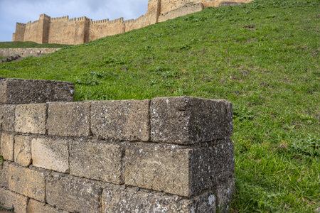 Ancient stone blocks form a wall. An ancient fortress is visible behind the ancient wall. The masonry of the stones forms a wall. An ancient fortress to protect people from attacks.の写真素材