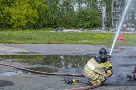 Firefighters hold the fire barrel when water is supplied under high pressure. Firefighters extinguish a fire at an oil refinery. Extinguishing fires at technological installations.の写真素材