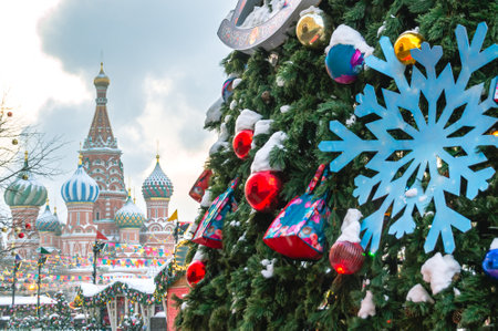 A Christmas tree with toys on Red Square against the background of St. Basil's Cathedral. New Year and festive mood. Branches of a Christmas tree with toys. New Year card.の写真素材