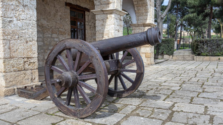 A fortress cast-iron cannon in an ancient fortress. Ancient weapons that fired cast-iron balls. Smooth bore cast iron cannon mounted on a wooden carriage.の写真素材