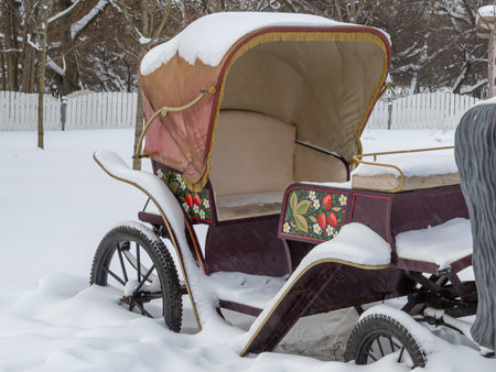 A light semi-open carriage for transporting passengers with the help of a horse. The britzka is standing in a snowdrift. An antique stroller.の写真素材