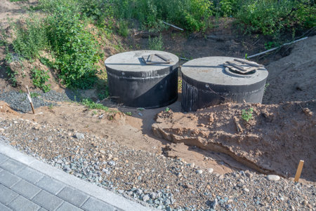 Installation of concrete sewer wells. Installation of sewer networks. Laying a pipeline underground. A trench for repairing the building's communications. Necks of sewer wells.の写真素材